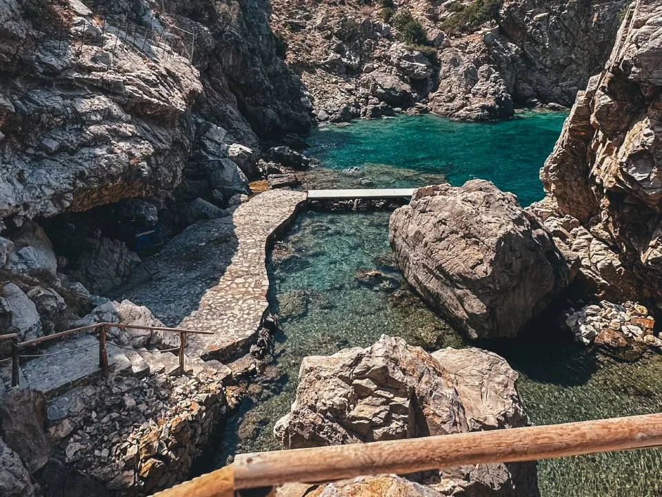 Stone path descending through cliffs to the private sea cove
